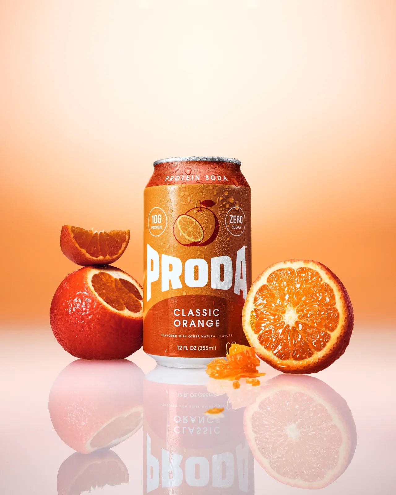 A can of PRODA Classic Orange between halved oranges on an orange backdrop