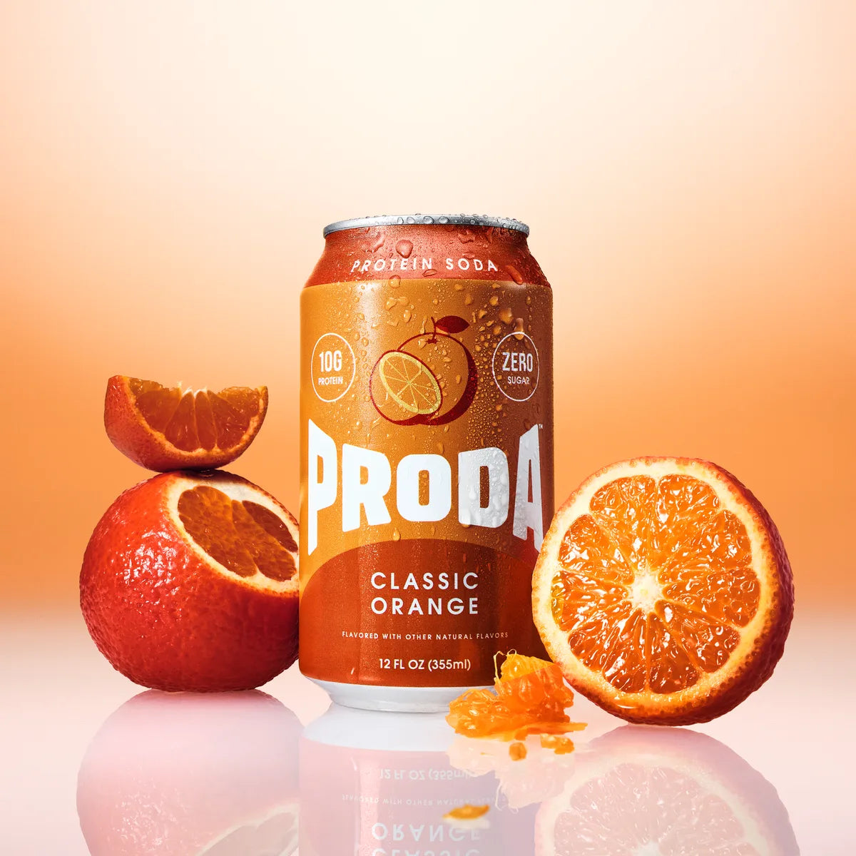 A can of PRODA Classic Orange between halved oranges on an orange backdrop