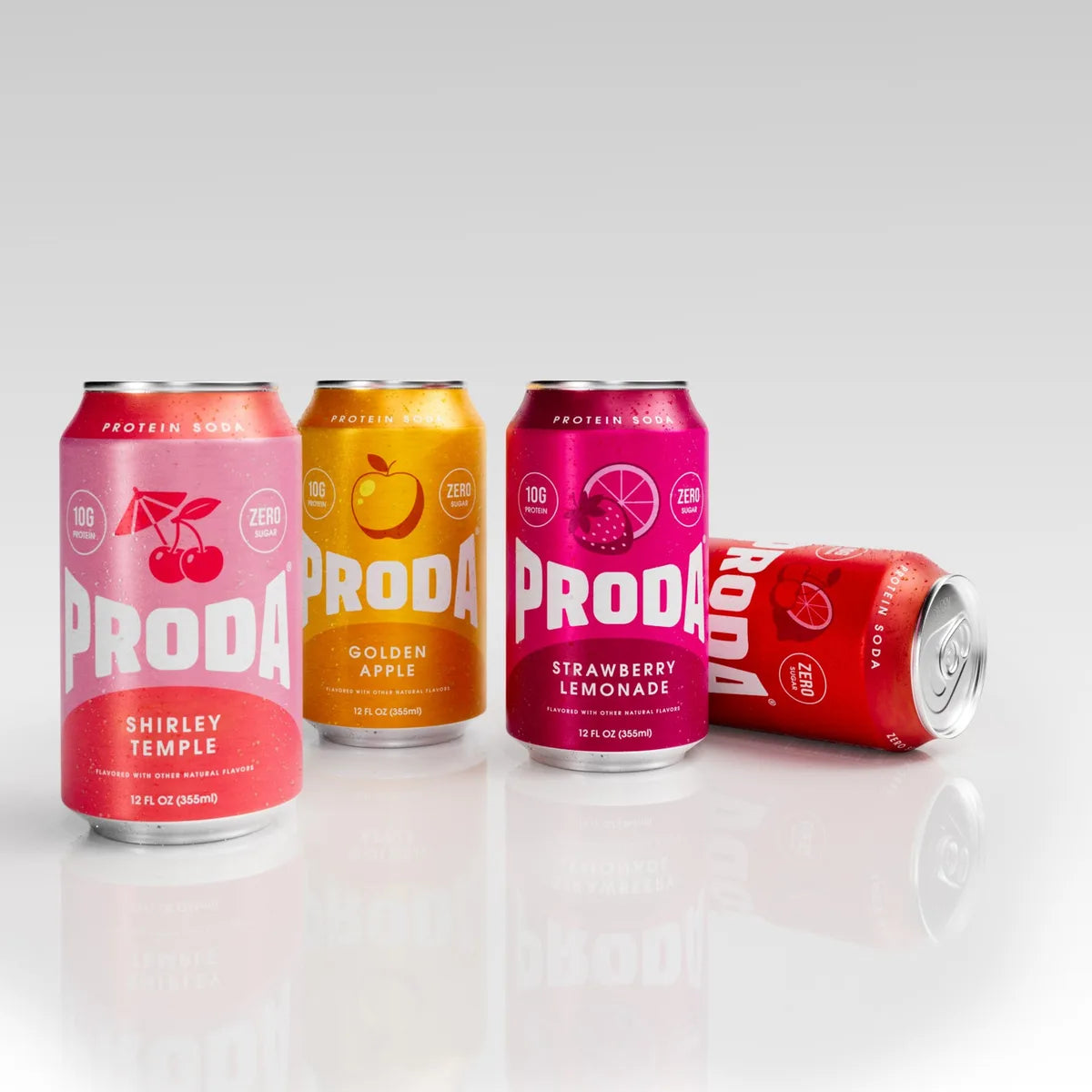 Cans of PRODA Shirley Temple, Golden Apple and Strawberry Lemonade standing, with Cherry Lime on its side