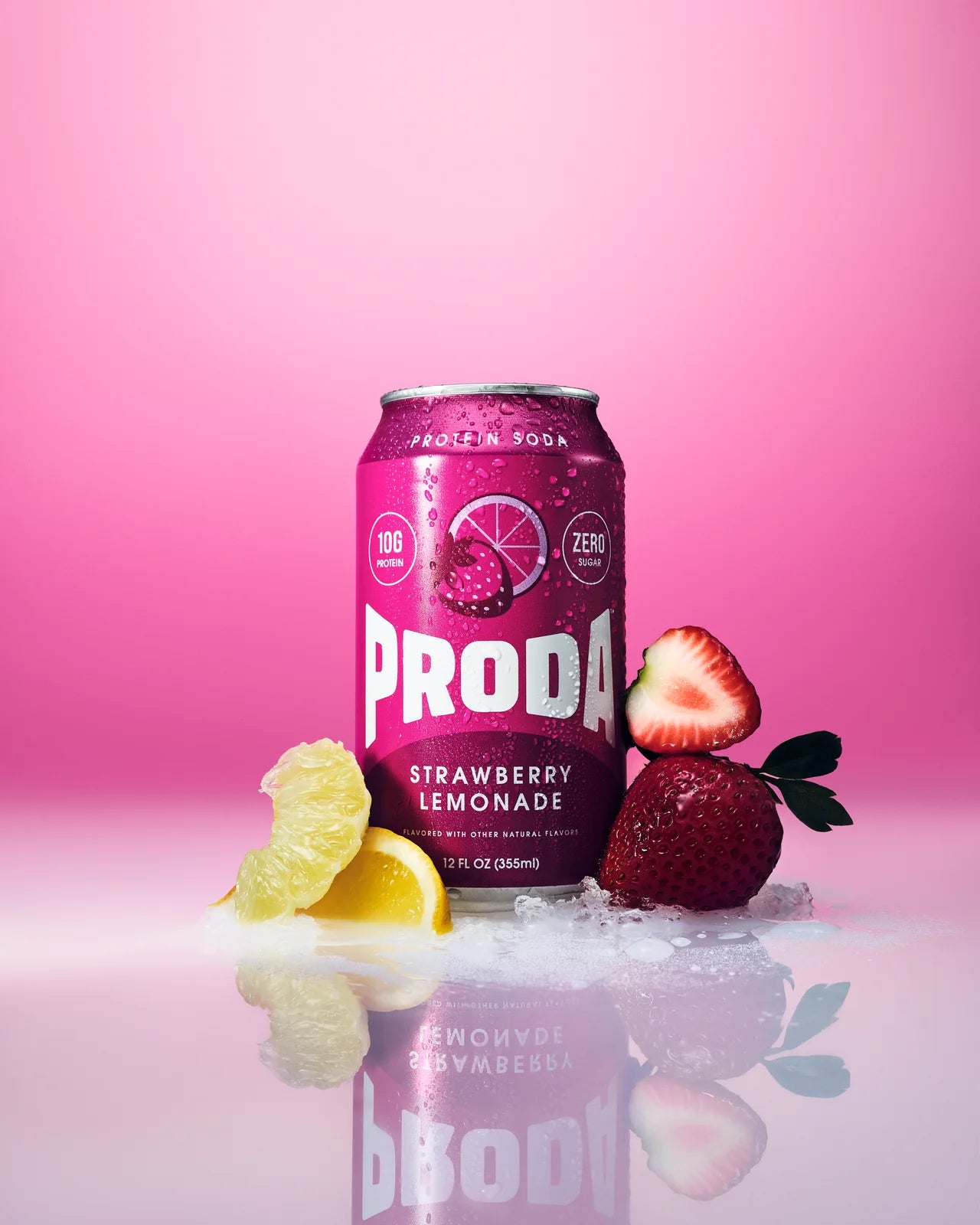 A can of PRODA Strawberry Lemonade with strawberries and lemon wedges on a pink backdrop